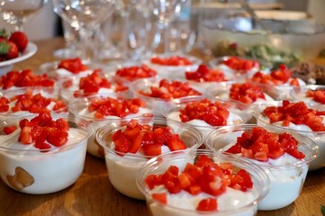Delicious strawberry sweet cream cheese deserts in small glass bowls. Woody table. Selected focus.