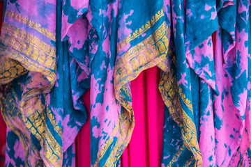 Background of colorful draped overlapping fabrics in pinks and turquoise with gold yellow...
