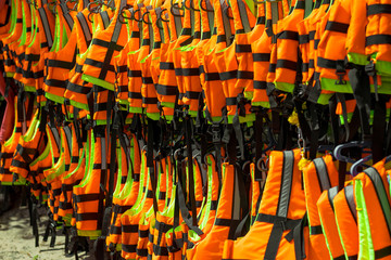 Bright orange life jackets. Life jackets are neatly hung on a rope and ready to use