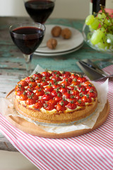 Tart, pie or cheesecake with cottage cheese and tomatoes, served with red wine on a wooden background.