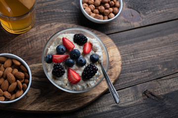 healthy breakfast. oatmeal with strawberries, blueberries, blackberries, almonds and hazelnuts with dried fruit compote