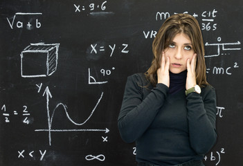 Stressed girl on the blackboard with mathematical formulas written in chalk on the background