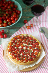 Tart, pie or cheesecake with cottage cheese and tomatoes, served with red wine on a wooden background.