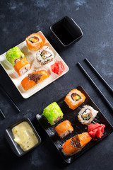 Various delicious sushi and rolls set on slate , sauce on dark stone background , flat lay