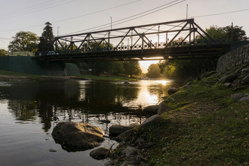 Iron bridge over the river against sunset