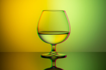Art glitch effect, glass glass with water on a bright multi-colored background, minimalism