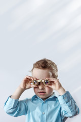 boy in a light shirt looking through binoculars on a light background