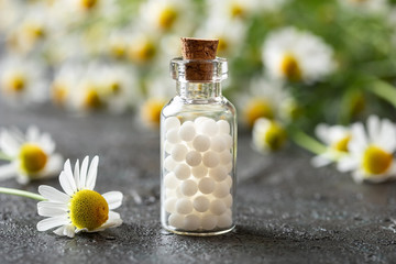 A bottle of homeopathic pills with chamomile flowers