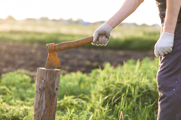 Man is chopping wood with vintage axe. close up, sunset