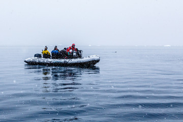 Snowfall over the Zodiac boat with frozen polar divers near Almirante Brown, Antarctic peninsula © vadim.nefedov