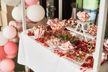 Wedding cake with decorative flowers and macarons on candy bar