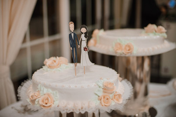 Wedding cake with funny figurines of groom and bride.
