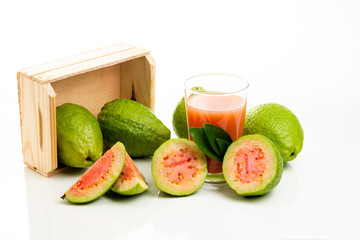 Wooden box with red guavas and cup with juice and pieces of fruit. Copy space.