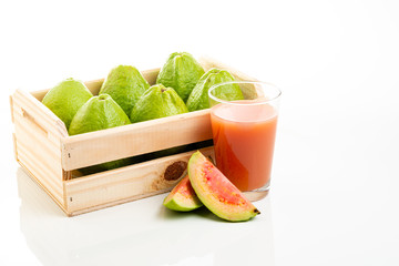 Wooden box with red guavas and cup with juice and pieces of fruit. Copy space.