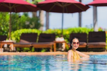 Portrait beautiful young asian woman leisure relax smile and happy around swimming pool in hotel resort