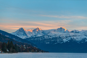 Fototapeta na wymiar Stuuning view of Eiger North Face Monch and Jungfrau in sunset from lake side of Thun