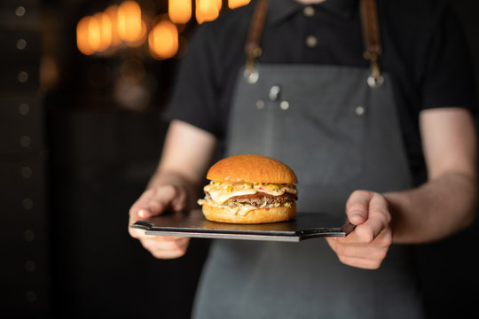 Waiter shot of chef carrying burger for client
