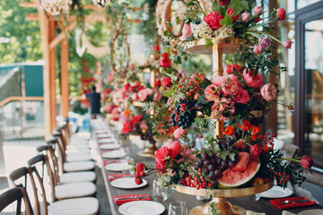 Wedding table flowers with fruits watermelon and berries decor in red white pink green colors.