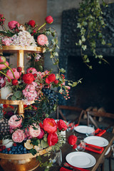 Wedding table flowers with fruits and berries decor in red white pink green colors.