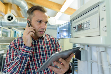 serviceman on telephone by electronic control panel