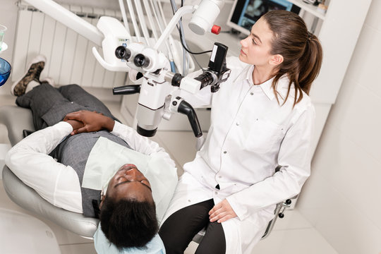 Female dentist advanced user, dental tools. Setup microscope for examining his patients teeth. in dental clinic office. Medicine, dentistry and health care concept.