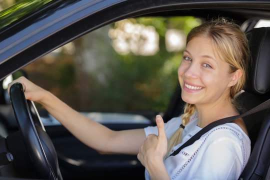 young woman shows thumbs up in her car