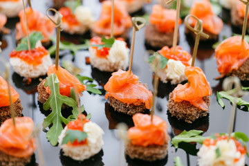 Buffet at the gala dinner. Assortment of canapes. Banquet service. catering food, snacks with salmon and caviar. rye, wheat bread.