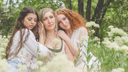 gypsy women in white flowered meadow in forest