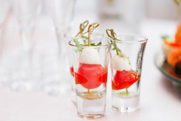 Appetizer, Caprese. Cherry tomatoes,mozzarella and Basil on skewers. . Pesto sauce. Buffet at the gala dinner. Assortment of canapes. Banquet service.