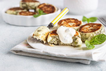 Cottage cheese fritters (syrniki) with green pea, dill, mint and sauce. Light stone background. Healthy breakfast or diet lunch. Copy space.