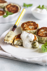 Cottage cheese fritters (syrniki) with green pea, dill, mint and sauce. Light stone background. Healthy breakfast or diet lunch. Copy space.