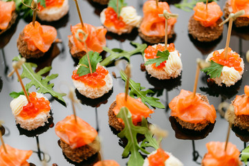 Buffet at the gala dinner. Assortment of canapes. Banquet service. catering food, snacks with salmon and caviar. rye, wheat bread.