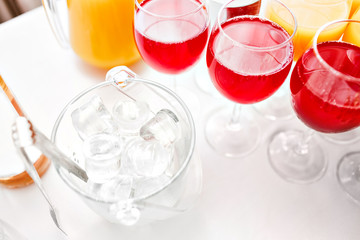 Table top full of glasses Glasses not alcoholic drinks, orange juice, water and berry juice. s with canapes and antipasti in the background.