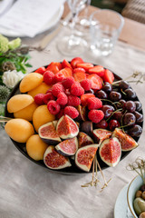 Table with cold snacks and tableware. Fresh Fruit platter on banquet table at business or wedding event venue. Raspberry, strawberry, cherry, Fig, apricote. Self service.