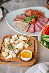 Cheese plate. Delicious cheese mix with walnuts, honey on wooden table. Tasting dish on a wooden plate. Food for wine. Buffet at the gala dinner.