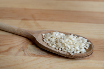 Rice on wooden spoon on wooden background. Concept of cooking and food