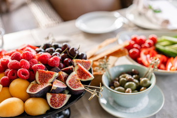 Table with cold snacks and tableware. Fresh Fruit platter on banquet table at business or wedding event venue. Raspberry, strawberry, cherry, Fig, apricote. Self service.