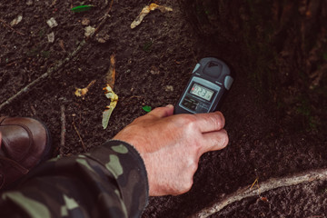 Chernobyl Exclusion Zone, Ukraine. Man holding in hand a Geiger counter, measures radiation level...