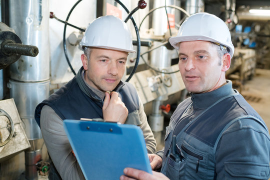 attentive factory worker writing on clipboard in factory - Powered by Adobe