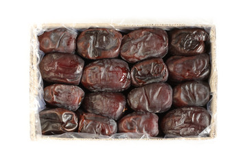 Dried dates arranged in rows in a cardboard box on white background. View from above