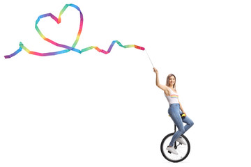 Young female riding a monocycle and holding a ribbon with a heart shape © Ljupco Smokovski
