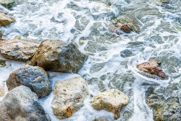 Sea foam on the rocky shore. Close-up, background. Space for text.