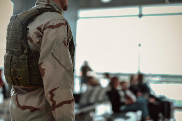 American soldier in camouflage standing in waiting room of airport