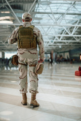 Back view of American soldier in camouflage walking in waiting room