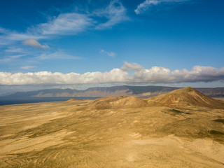 Aerial view of a desert landscape on the island of Lanzarote, Canary Islands, Spain. Mountains of the village of Soo and in the background Famara. Reliefs and volcanoes on the horizon