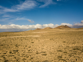 Aerial view of a desert landscape on the island of Lanzarote, Canary Islands, Spain. Mountains of the village of Soo and in the background Famara. Reliefs and volcanoes on the horizon