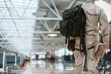 Cropped photo of American soldier in camouflage carrying backpack