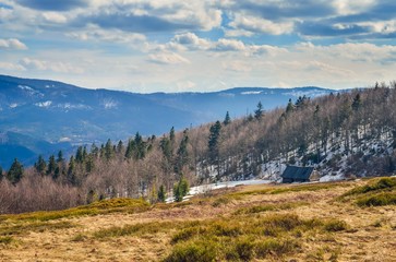 Fototapeta premium Fabulous spring mountain landscape. Wooden cabin on a clearing on a hill.
