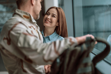 Happy young couple looking at each other while standing near window