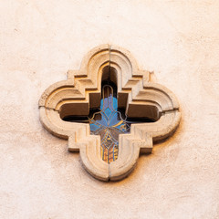 exterior view of an architectural detail on an adobe chapel building in the Tlaquepaque Arts & Shopping Village in Sedona, Arizona with stained glass cross shaped window